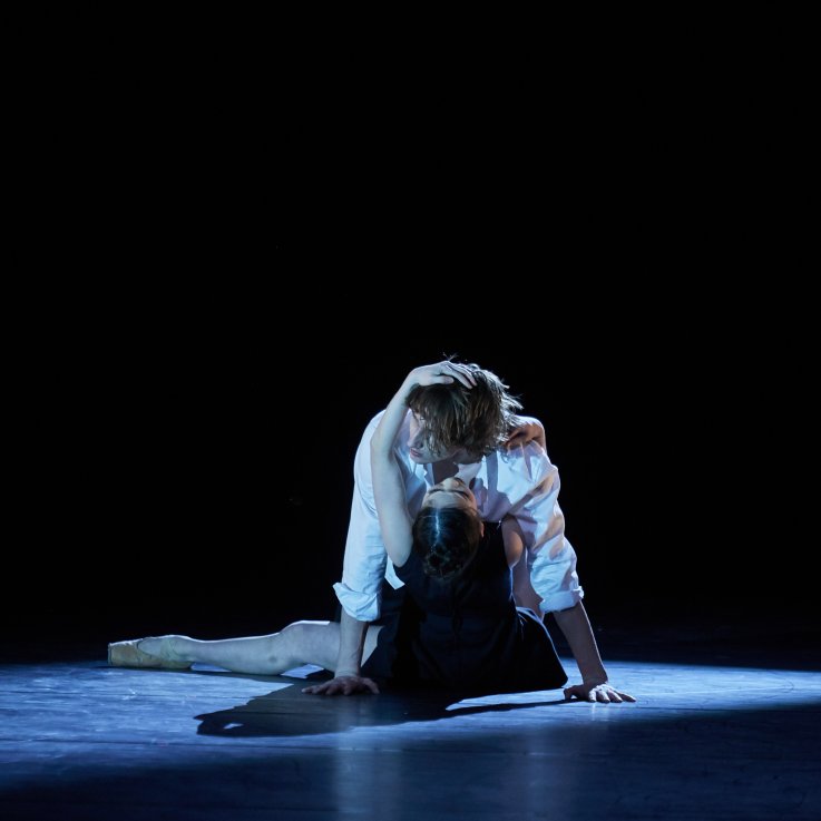 para tancerzy w trakcie spektaklu na zaciemnionej scenie